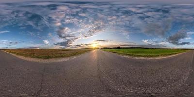 panorama esférico completo sin costuras vista en ángulo de 360 grados en la carretera asfaltada entre los campos en la puesta de sol de la tarde de verano con nubes impresionantes en proyección equirectangular, skybox vr ar contenido de realidad virtual foto