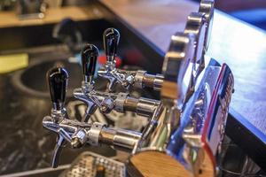 fila de grúas para cerveza artesanal embotellada y bebidas en el bar de élite foto