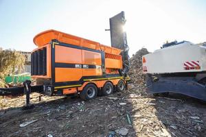 Excavator sorts plastic garbage at waste processing plant. Separate garbage collection. Recycling and storage of waste for further disposal. Business for sorting and processing of waste. photo