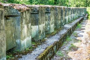 protective concrete mossy wall of ruined abandoned military fortress of the First World War in forest photo