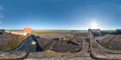 Aerial full spherical seamless 360 degrees angle view panorama with roof concrete abandoned unfinished building of airport on runway in equirectangular equidistant projection, VR AR content photo