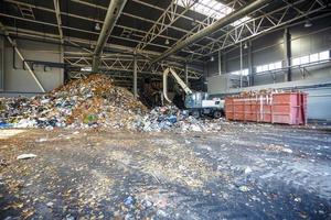 Excavator on primary sorting of garbage at waste processing plant. Separate garbage collection. Recycling and storage of waste for further disposal. Business for sorting and processing of waste. photo