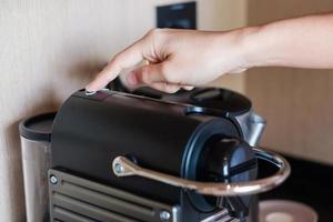 Hand making Espresso by Coffee Machine with capsules on wood table photo