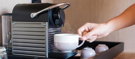 Hand making Espresso by Coffee Machine with capsules on wood table photo