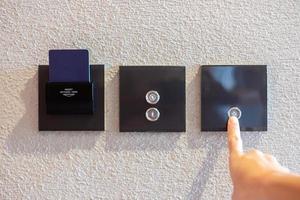 finger turn on or off on modern light switch on wall at home. Energy Saving, power, electrical and lifestyle concepts photo