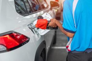 mano de hombre repostar al coche, boquilla de combustible de gasolina en el vehículo en la gasolinera. precio del petróleo, economía del petróleo, inflación y concepto de productos básicos foto