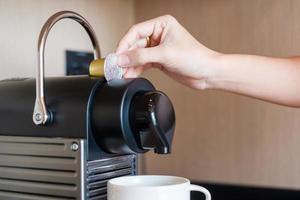 Hand making Espresso by Coffee Machine with capsules on wood table photo