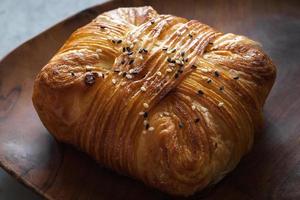 Ham Pastry with sesame sprinkle, look at the texture, buttery fresh on wooden tray, marble table  background. Shoot close up photo