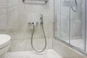 details of corner shower cabin with wall mount shower attachment and water tap sink with faucet in expensive bathroom photo