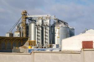 agro silos granary elevator in winter day in snowy field. Silos on agro-processing manufacturing plant for processing drying cleaning and storage of agricultural products, flour, cereals and grain. photo