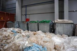 Containers with used bottles and  plastic bales of rubbish at waste treatment processing plant. Recycling separatee and storage of garbage for further disposal, trash sorting. photo