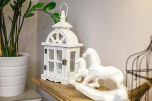 interior decoration toys. White decorative wooden latern lights and ceramic horses in expensive interior photo