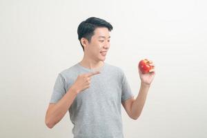 young Asian man with glass of water and apple on hand photo