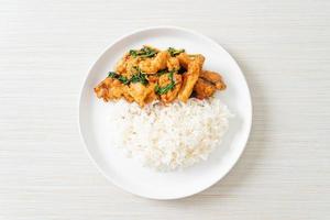 stir-fried fried fish with basil and chili in thai style topped on rice photo