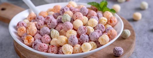 Colorful cereal corn balls mix sweets in a bowl on gray cement background. photo