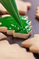 primer plano de dibujo de galletas de azúcar de árbol de Navidad sobre fondo de mesa de madera con glaseado. foto