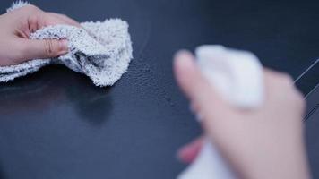 Woman housekeeper using rag and spraying bottle to clean the table surface. photo