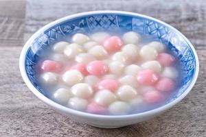 Close up of red and white tangyuan in blue bowl on wooden background for Winter solstice. photo