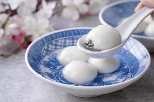 primer plano de tangyuan yuanxiao en un recipiente sobre una mesa gris, comida para el solsticio de invierno. foto