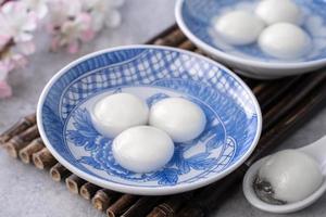 primer plano de tangyuan yuanxiao en un recipiente sobre una mesa gris, comida para el solsticio de invierno. foto