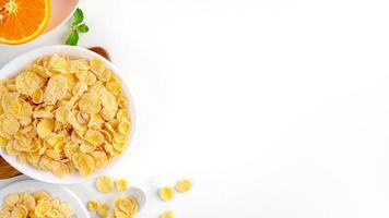 Top view of corn flakes bowl with milk on white background. photo