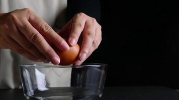 chef señora poniendo huevo en un tazón de vidrio mientras hace pasteles caseros sobre fondo negro video