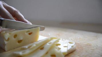 donna tagliata a fette di formaggio per cucinare usando il coltello in cucina - persone che producono cibo con il concetto di formaggio video