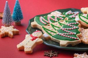 Close up of Christmas sugar cooikes in a plate on red table background. photo