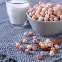 bolas de maíz de cereales de colores mezclan dulces en un bol sobre fondo de cemento gris. foto