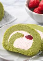 deliciosas rebanadas de pastel de matcha swiss roll con crema de fresa sobre fondo blanco. foto