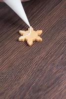 Close up of drawing Christmas snowflake sugar cookie on wooden table background with icing. photo