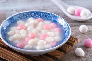 Close up of red and white tangyuan in blue bowl on wooden background for Winter solstice. photo