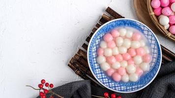 vista superior de tangyuan rojo y blanco en un tazón azul sobre fondo blanco para el solsticio de invierno. foto