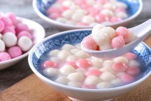 primer plano de tangyuan rojo y blanco en un tazón azul sobre fondo de madera para el solsticio de invierno. foto