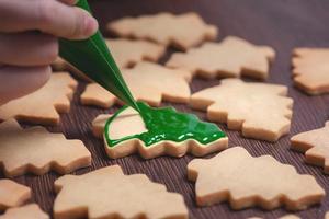 Close up of drawing Christmas tree sugar cookie on wooden table background with icing. photo