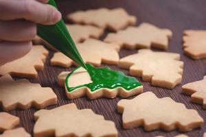 primer plano de dibujo de galletas de azúcar de árbol de Navidad sobre fondo de mesa de madera con glaseado. foto