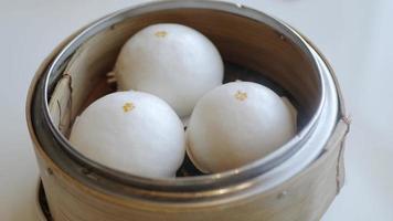 hand while picking chinese cream bun dimsum from basket steamer in chinese re video
