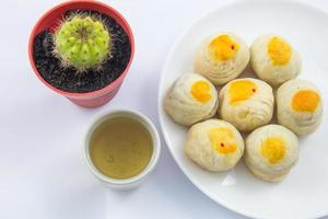Chinese Pastry Mung Bean or Mooncake with Egg Yolk on dish and green tea cup and cactus pot