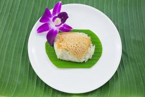 arroz pegajoso con natillas al vapor en hojas de plátano y plato con flor de orquídea, arroz pegajoso dulce, postre dulce tailandés, comida tailandesa original foto