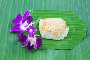 arroz pegajoso con natillas al vapor con flor de orquídea en hojas de plátano, arroz pegajoso dulce, postre dulce tailandés, comida tailandesa original foto