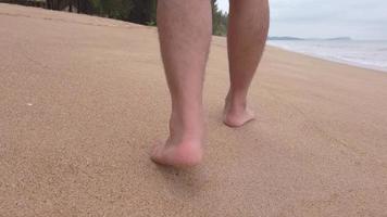 de hombre caminando con los pies descalzos en la playa de arena blanca en cámara lenta en verano ho video
