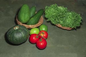 Combination of fruits and vegetables for salad avocado pumpkin green lemon tomato and lettuce on wood table close up. photo