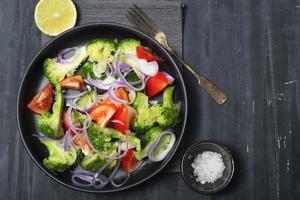 Healthy food vegetable broccoli salad in bowl on black wood background. photo