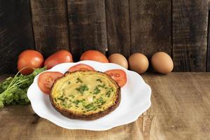 Egg breakfast food omelet has vegetable in plate on wood table. photo