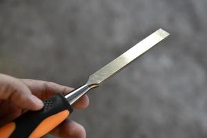 Steel chisel on wood in the hands. Carpentry iron hand tools. photo