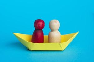 parejas en barco de papel amarillo con fondo azul. concepto de relación. foto