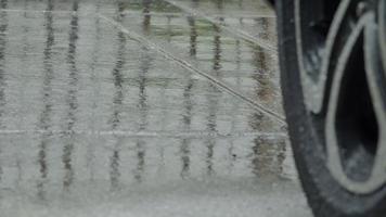 salpicaduras de lluvia y neumáticos de coche en agua de lluvia. estacionamiento de autos bajo la lluvia. video