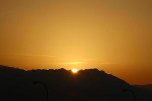 amanecer en el mar muerto en israel. el sol sale de detrás de las montañas en jordania. foto