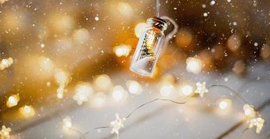 Fairy lights in a jar with a Christmas tree and snow close-up on a warm cozy mood with golden garland. Christmas and New Year, festive decor, copy space. Christmas background photo