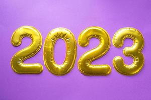 Happy New Year- golden numbers 2023 on a purple background with sequins, stars, glitter, lights of garlands. Greetings, postcard. Calendar, cover. photo